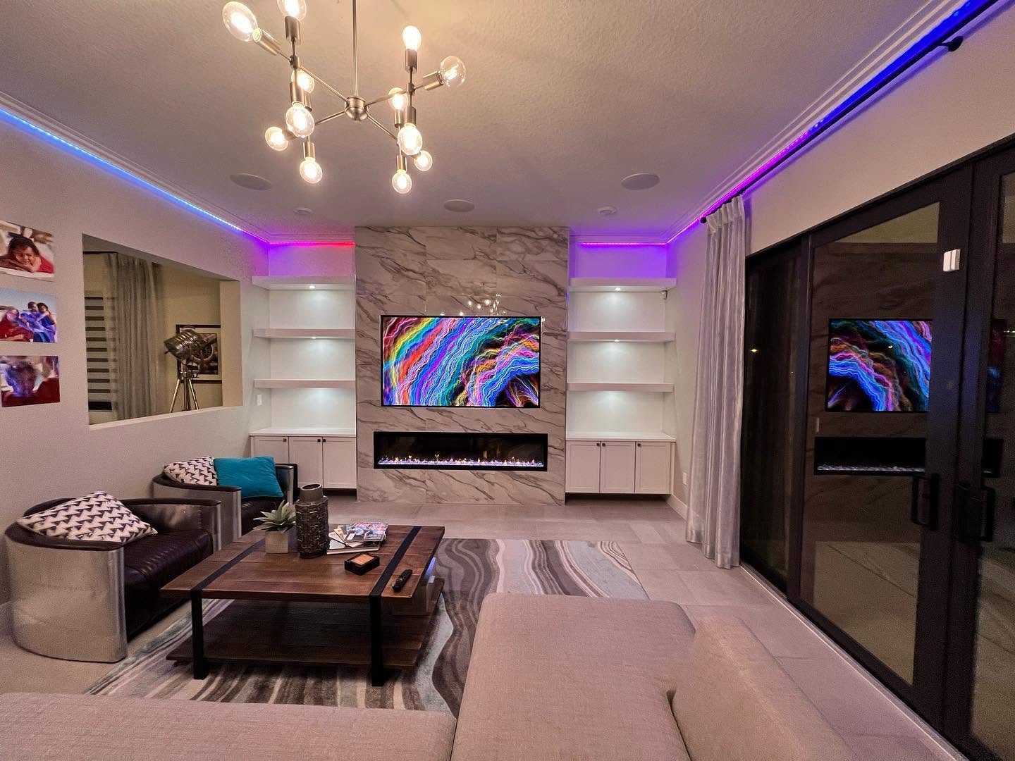 Furnished lounge with a marble feature wall, linear fireplace, built-in shelving and cove lighting.