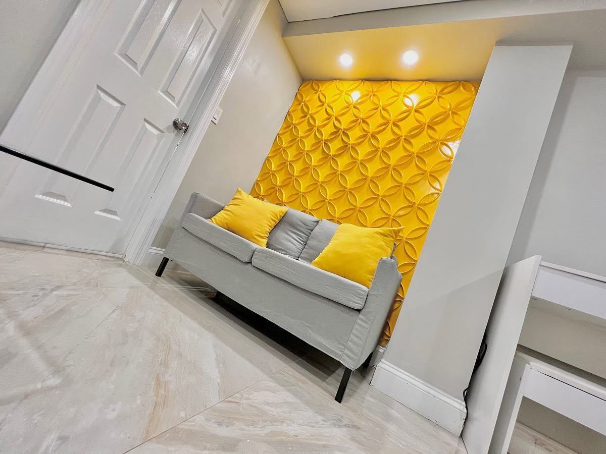 Custom 3D geometric accent wall panel, uplit from a recessed ceiling detail.