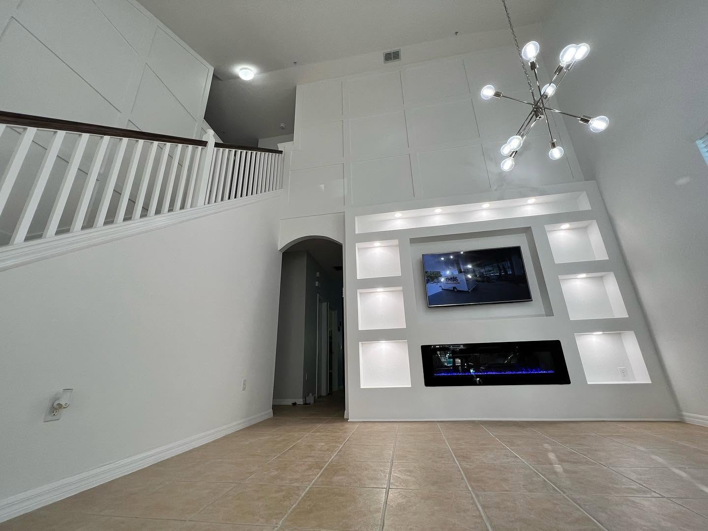 Two-story great room with a lit-niche media wall and full-height paneled trim.