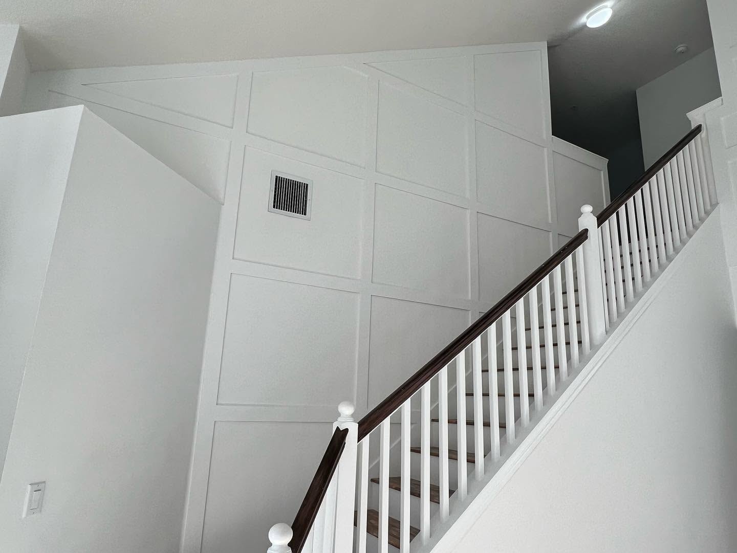 Custom square-grid paneled feature wall running the full height of a staircase.