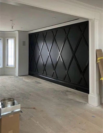 Full-height black accent wall with a custom diamond trim pattern in a newly finished room.