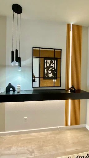 Bar surround finished in wood and black panelling with pendant lighting above the counter.
