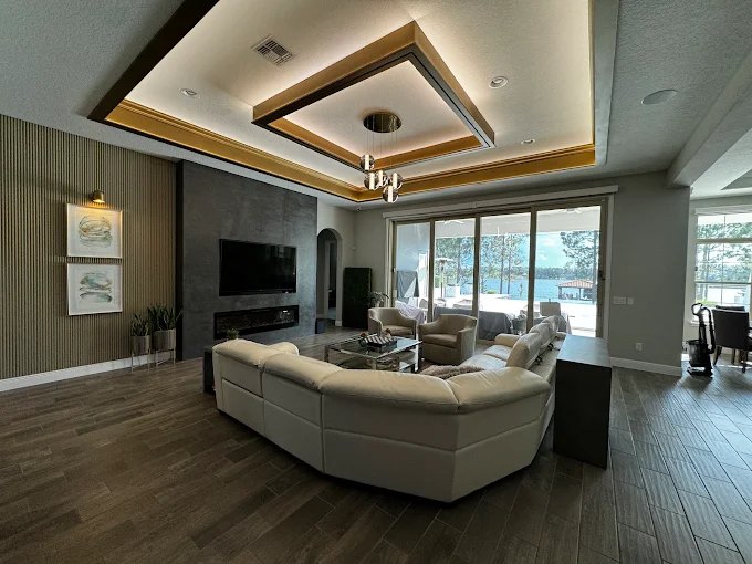 Open living room with a custom tray ceiling detail, wall-mounted television and built-in cabinetry.